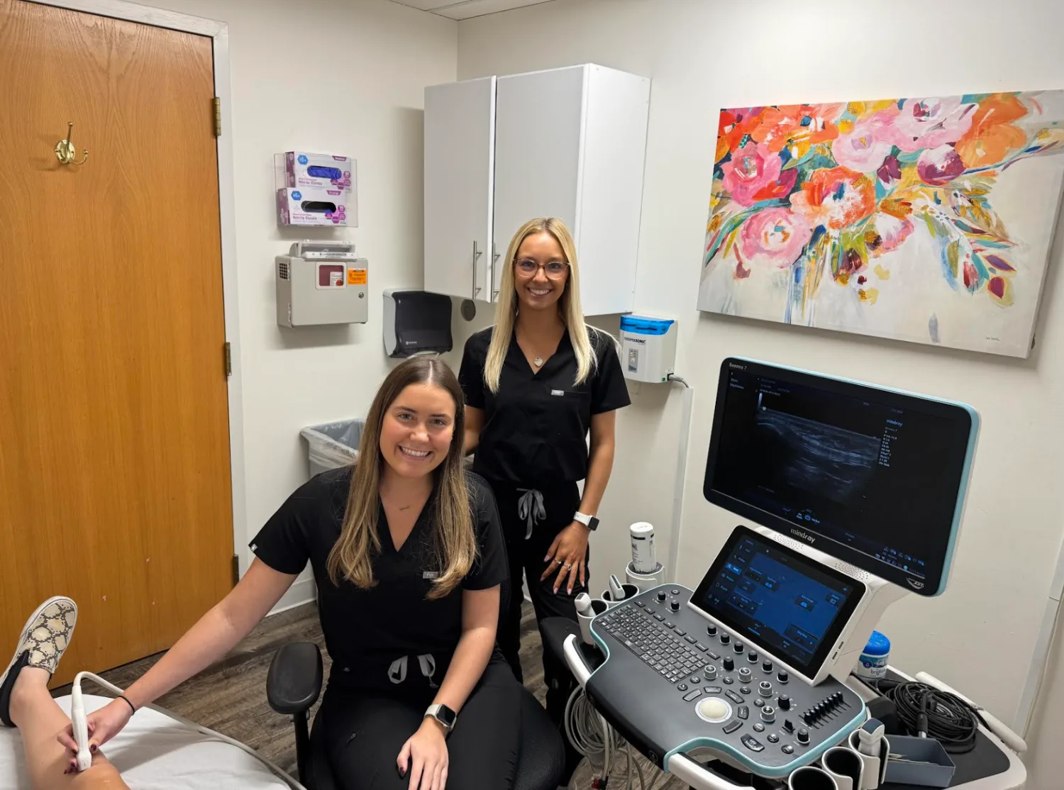 Two registered sonographers at Ultrasound First beside an ultrasound system during an exam