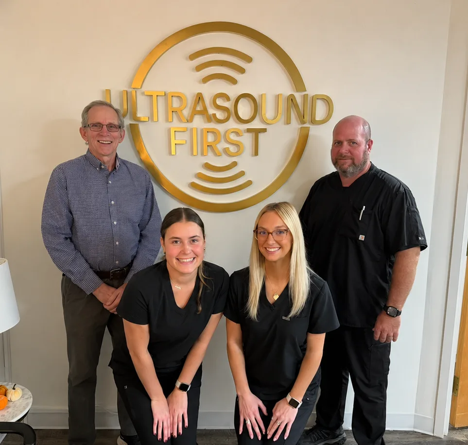 The Ultrasound First team standing together beneath the practice logo