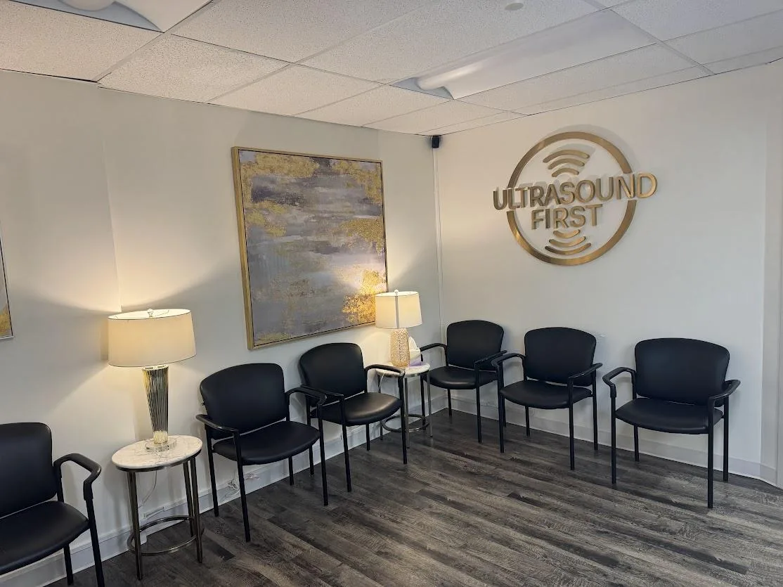 A quiet waiting room with lamp light, framed artwork, and the practice logo on the wall