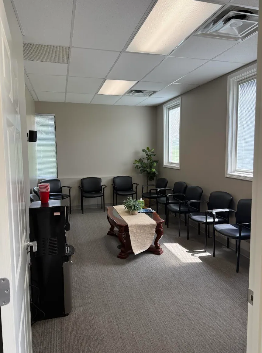 A sunlit waiting room with seating around a low table and a water station
